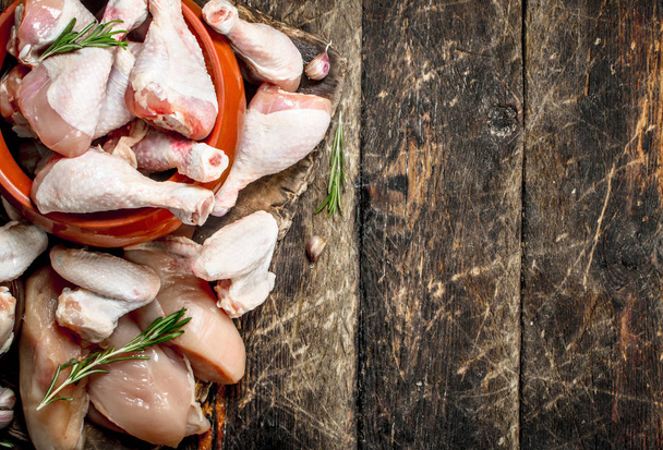 Various types of raw chicken meat with herbs in a bowl. On wooden background. - Φωτογραφία, εικόνα