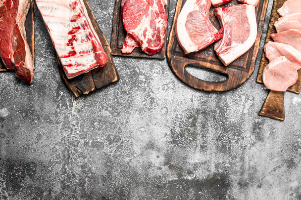 Different types of raw meat on the boards. On rustic background. - Photo, Image