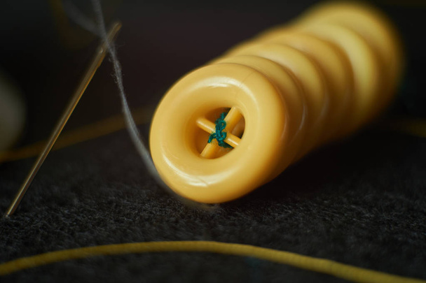 Linha de botões de roupas amarelas, agulha com fio na agulha pu
 - Foto, Imagem