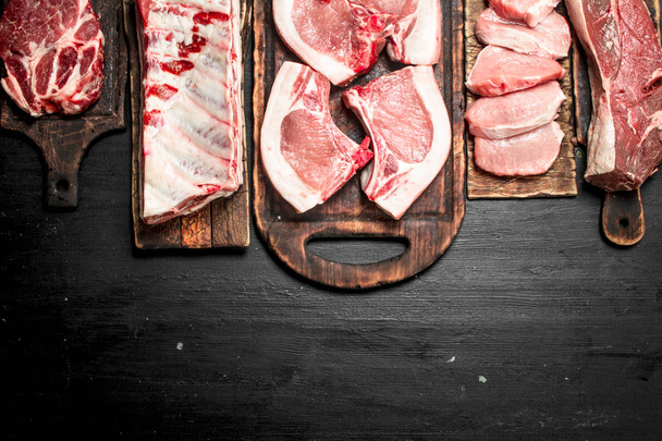 Different types of raw pork meat and beef. On the black chalkboard. - Photo, image