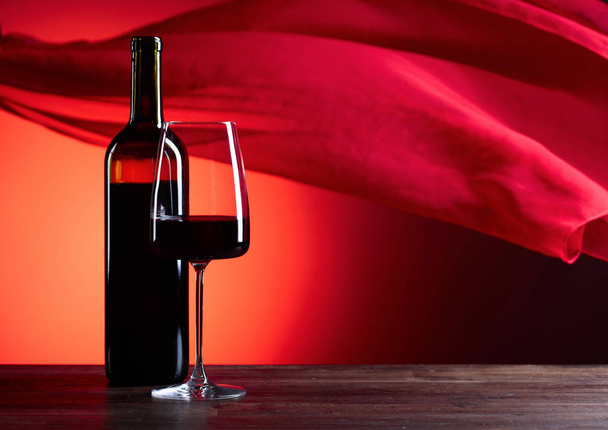メガネと赤い背景の上の助言のワインのボトル。赤の薄い f - 写真・画像