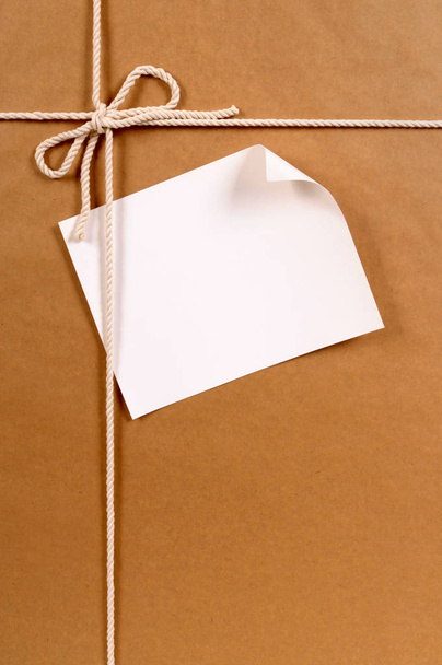 Brown paper package with curled label - Фото, изображение