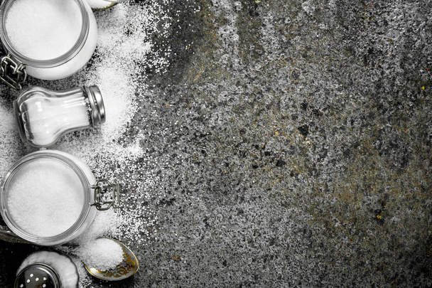 Salt in jars and spoons. On rustic background. - Foto, Imagen
