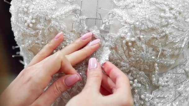 彼のスタジオで花嫁のためクローズ アップ ファッション ・ デザイナーはピン針レースのウェディング ドレスです。仕立て屋は、ウェディング ドレスを作成します。ピンと針のアウトラインで固定します。小さい個人的なビジネス。縫う - 映像、動画