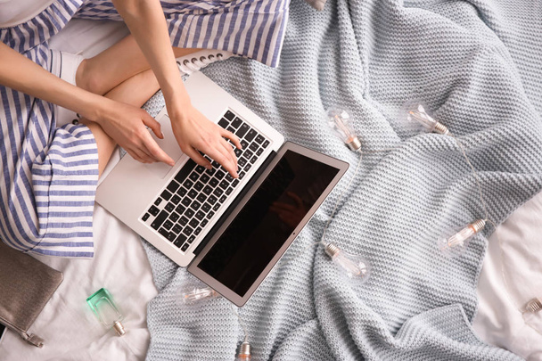 Female blogger with laptop on bed, top view - Valokuva, kuva