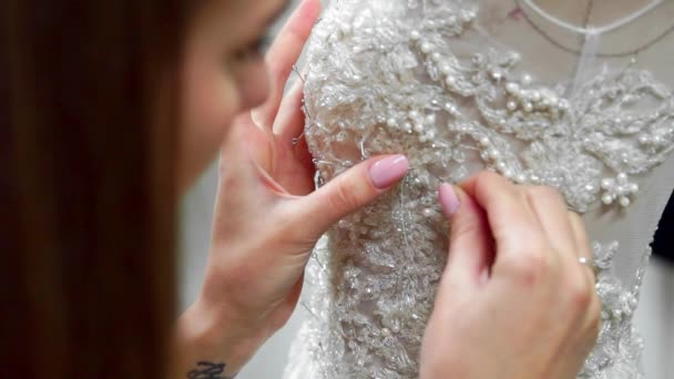 Módní návrhářka pro nevěsty v jeho ateliéru detail piny jehly krajkové svatební šaty. Švadlena vytváří exkluzivní svatební šaty. Zajistěte s obrysem špendlíky a jehly. Malé soukromé firmy. Šít - Záběry, video