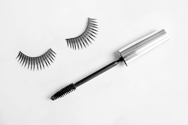 Mascara brush and false eyelashes on grey background, flat lay - Fotoğraf, Görsel