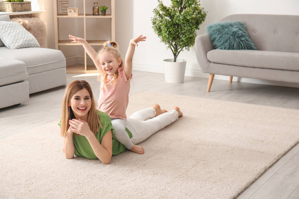 Cute little girl and her mother on cozy carpet at home - Zdjęcie, obraz