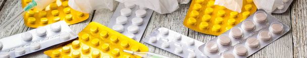 Banner mit Medikamenten, Spritze, Thermometer und Pillen auf weißem Holzgrund - Foto, Bild