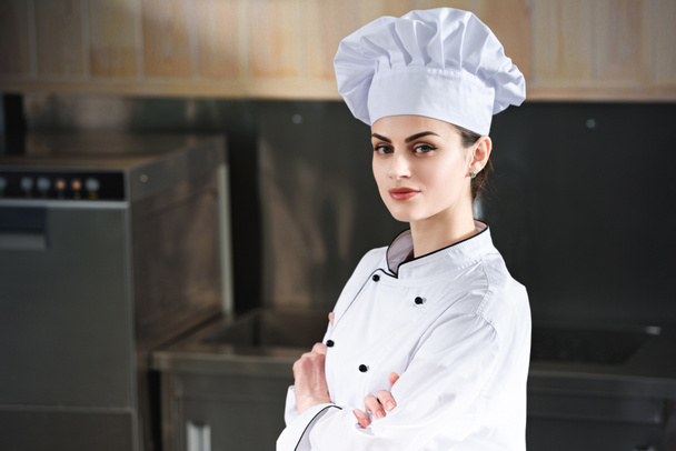 Professional female chef standing with arms folded on modern kitchen - Fotoğraf, Görsel
