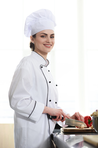 Profi-Köchin schneidet Paprika auf Küchentisch - Foto, Bild