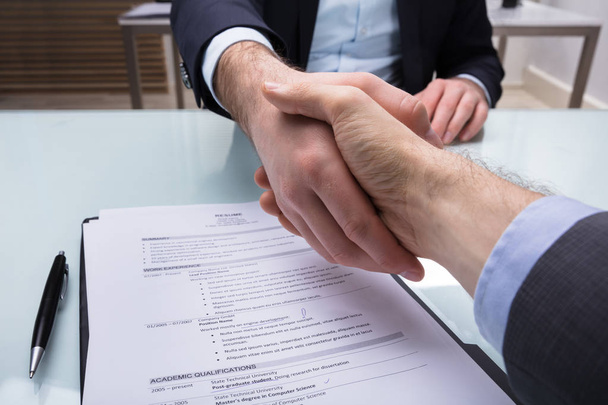 Przedsiębiorca i wnioskodawca drżenie dłoni z CV na biurko - Zdjęcie, obraz