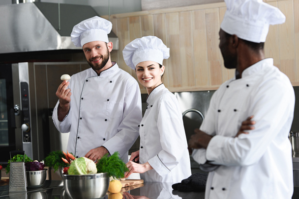 Многорасовая команда поваров выбирает кулинарные ингредиенты на современной кухне
 - Фото, изображение