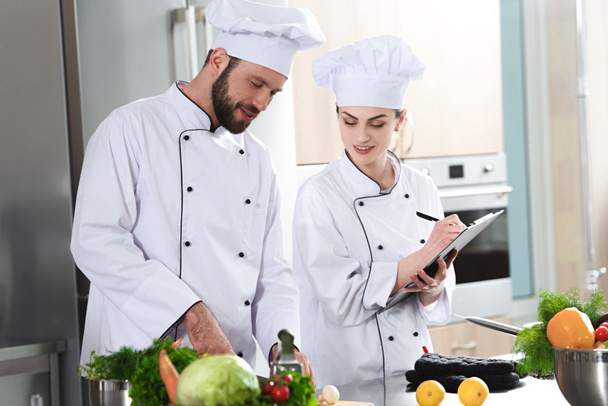 Equipe profissional de cozinheiros verificando a receita durante o prato de cozinha
 - Foto, Imagem