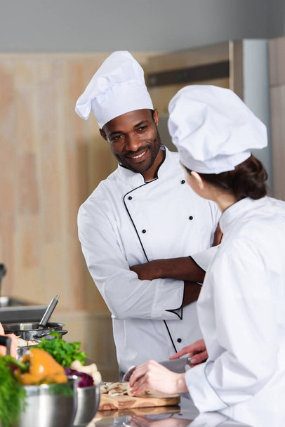 Multiracial team of cooks talking while cooking on modern kitchen - Foto, Imagem