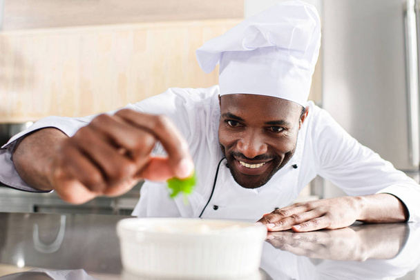 African american chef garnishing dish on restaurant kitchen - Фото, изображение