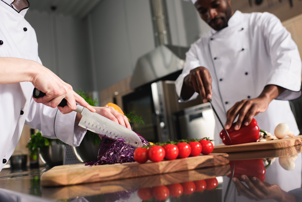 Multiracial chefs team cutting raw vegetables in kitchen - Foto, Imagem