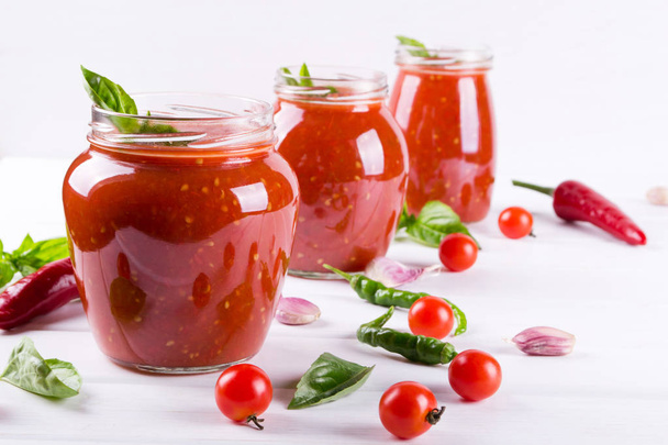 Tomatensauce, Ketchup im Glas und Zutaten auf weißem Hintergrund  - Foto, Bild
