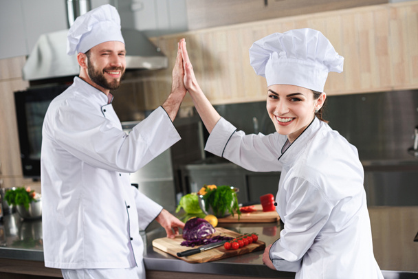 Professional chefs giving high five on modern kitchen - Photo, Image