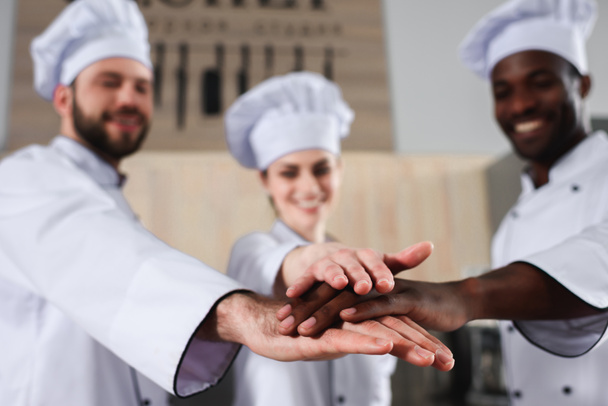 Tram multiracial de cuisiniers empilant les mains ensemble sur la cuisine moderne
 - Photo, image