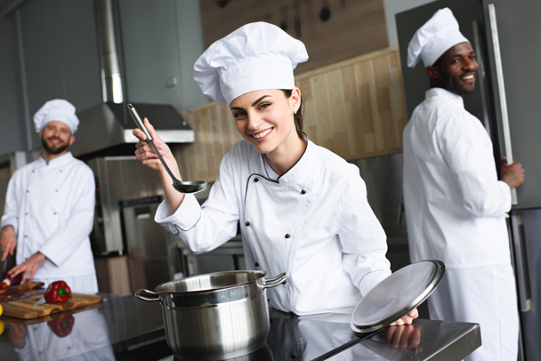 Vrouwelijke chef-kok proeven schotel door haar multiraciale team - Foto, afbeelding