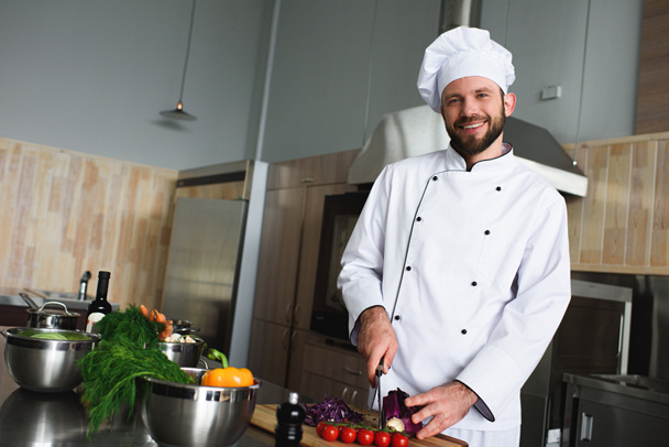 Chef professionnel coupant des légumes sur la table de cuisine
 - Photo, image