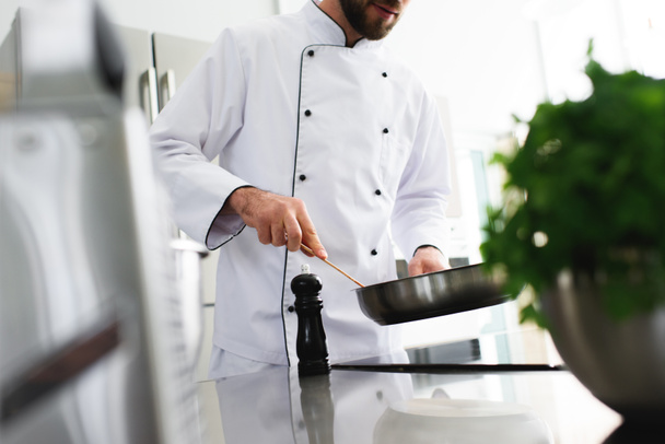 imagem cortada do chef fritando comida na frigideira na cozinha do restaurante
 - Foto, Imagem