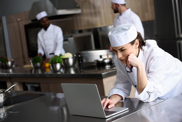 attractive chef using laptop at restaurant kitchen - Foto, imagen