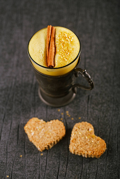 Latte de cúrcuma o leche dorada con galletas sobre fondo de madera
 - Foto, imagen