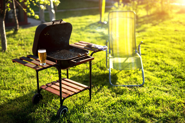 Grill leaned, glass full of bear and everything is ready for a beautiful picnic on a sunny day. - Фото, изображение