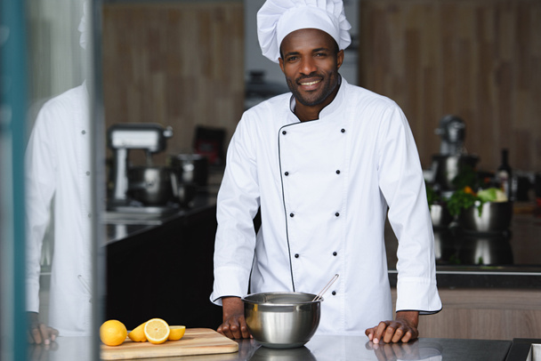 guapo afroamericano chef de pie cerca del mostrador de cocina en la cocina del restaurante
 - Foto, Imagen