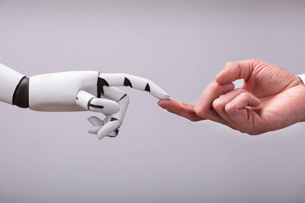 Robot Touching Human Finger Against Gray Background - Photo, image
