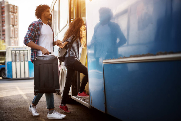 旅行かばんを持つ青いバスに入る若いカップル - 写真・画像