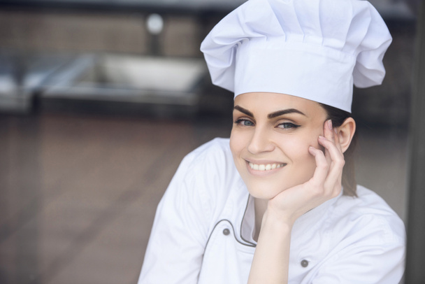 sonriente atractivo chef mirando a la cámara en la cocina del restaurante
 - Foto, Imagen