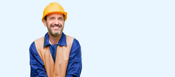 Senior engineer man, construction worker thinking and looking up expressing doubt and wonder isolated over blue background - Photo, Image