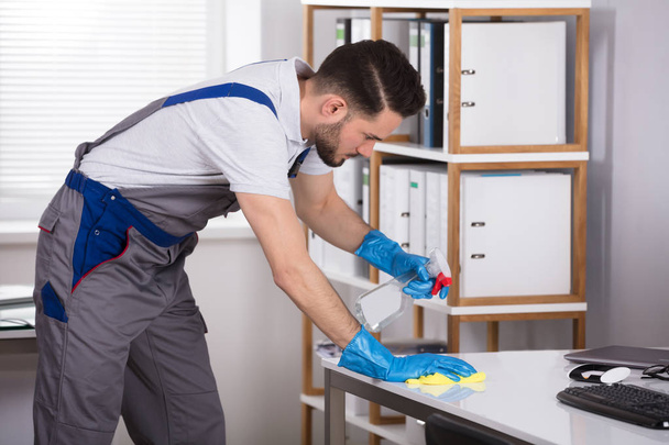 Close-up Of A Young Man Cleaning Desk In Office - Foto, immagini
