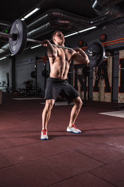 Young man at a crossfit gym lifting a barbell. - Фото, зображення