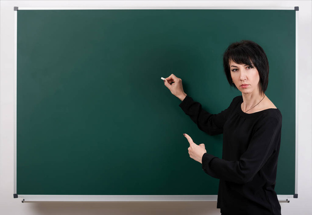 Strenger Lehrer posiert mit Kreidetafel, Lernkonzept, grüner Hintergrund, Studioaufnahme - Foto, Bild
