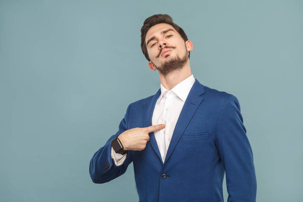 портрет гордого бизнесмена, смотрящего в камеру и указывающего пальцем на себя на светло-голубом фоне, концепцию богатых и успешных деловых людей
  - Фото, изображение