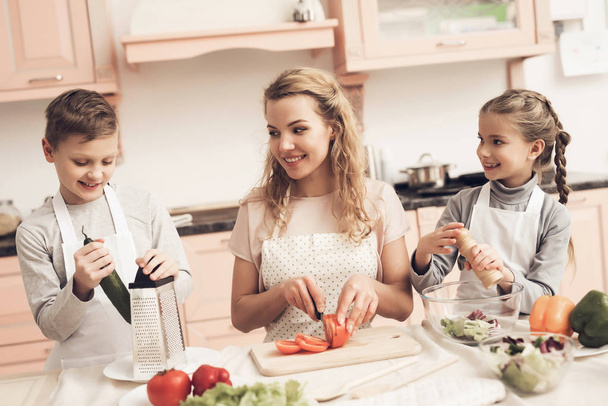 Children with mother preparing vegetables for salad at kitchen  - Foto, Bild