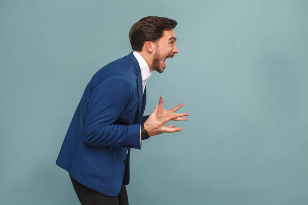 profile view of stressed manager in work shouting on light blue background, concept of richly and success business people  - 写真・画像