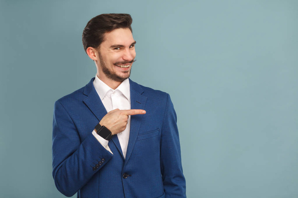 funny man in suit pointing finger aside on light blue background, concept of richly and success business people  - Foto, Bild