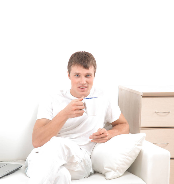 Handsome casual man sitting on couch having coffee at home. - 写真・画像