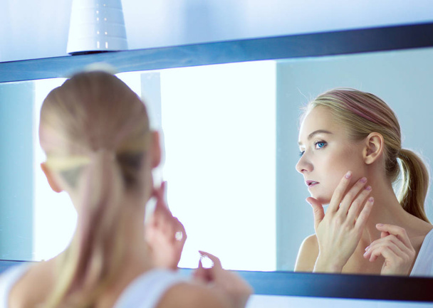 Face of young beautiful healthy woman and reflection in the mirror - 写真・画像