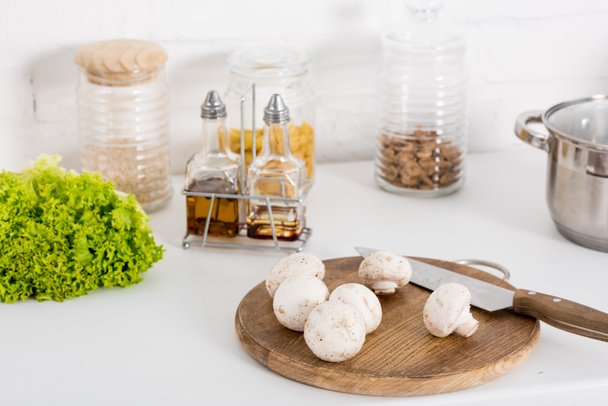 ингредиенты и грибы на деревянной доске с ножом на кухне
 - Фото, изображение