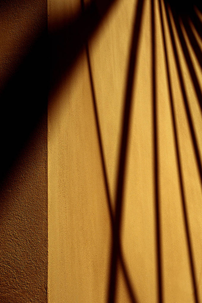 künstlerische abstrakte Fotografie dunkler Schatten an der Wand. Farbdetailaufnahmen von Schatten und Sonnenlicht auf einer braunen Betonwand. Moden Architektur Detail. - Foto, Bild