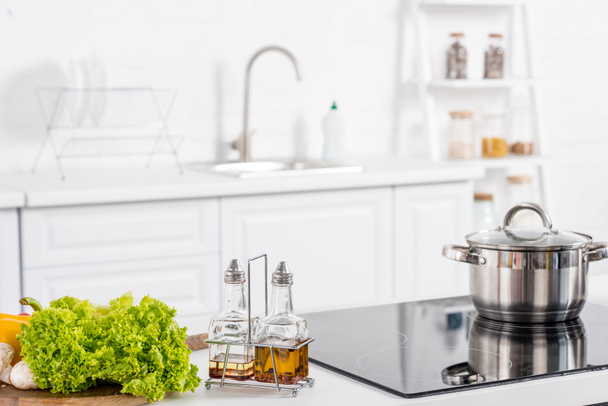 fresh ingredientes and electric stove with saucepan on kitchen - Φωτογραφία, εικόνα