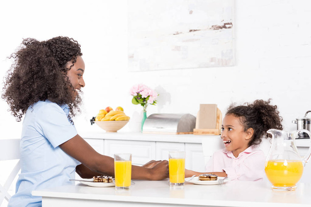 african american matka i córka o naleśniki i sok pomarańczowy na śniadanie w jadalni - Zdjęcie, obraz