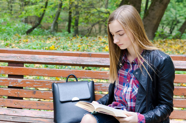 Menina adolescente bonita lendo um livro. Adolescente ou jovem adulto do ensino médio ou estudante universitário estudando no parque. Espaço de cópia
. - Foto, Imagem