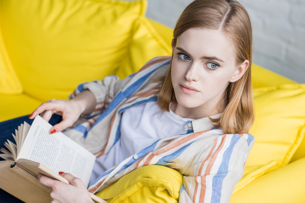 stylish young woman holding book and looking away  - Valokuva, kuva